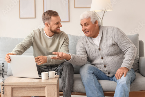 Foto Senior man with his son watching something on laptop at home