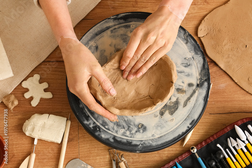 Young woman forming clay pl...