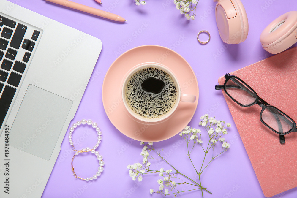 Naklejka premium Cup of coffee with laptop, notebook, headphones, eyeglasses, jewelry and gypsophila flowers on purple background