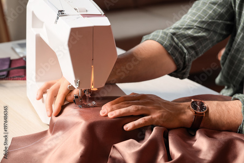 Young male tailor using sew...