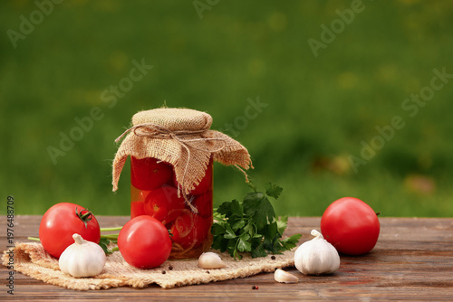 Jar of canned tomatoes with garlic and parsley on wooden table outside