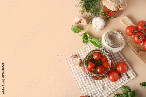 Jar of tasty canned tomatoes with garlic and basil leaves on beige background