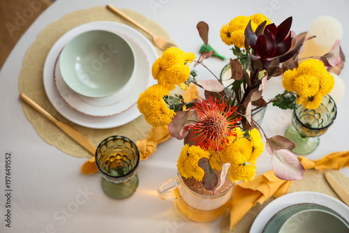 Beautiful table setting with bouquet of flowers, tea and candles in light dining room, top view