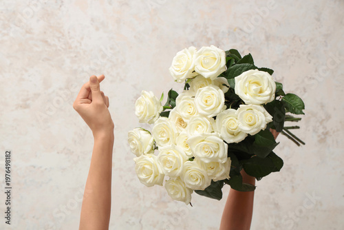 Woman's hands holding bouquet of beautiful white roses on light background