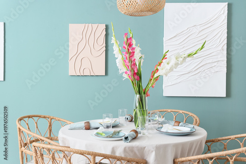 Elegant table setting with plates, glasses and beautiful gladiolus flowers