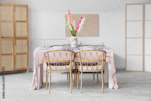 Served dining table with plates and beautiful gladiolus flowers in interior of stylish dining room