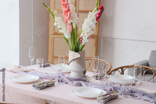 Elegant table setting with plates, glasses and beautiful gladiolus flowers