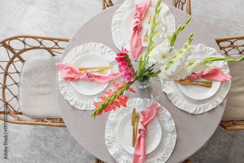 Elegant table setting with plates, golden cutlery and beautiful gladiolus flowers, top view