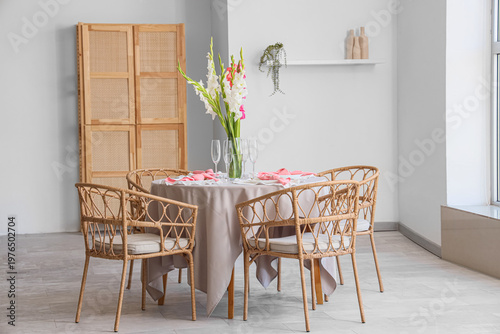 Served dining table with plates and beautiful gladiolus flowers in interior of stylish dining room