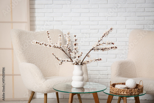 Interior of living room with armchairs, tables and blooming branches