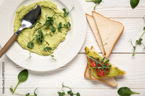Composition with plate of tasty avocado hummus, fresh sprouts and bread on light wooden background