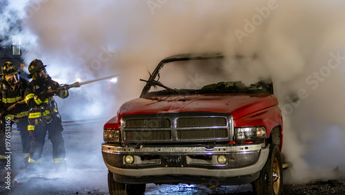 Schilderij op canvas Firefighters work to put out flames coming from a red truck