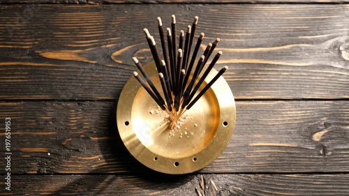 Burning incense sticks in a brass holder on a dark wooden background, smoke rising, creating a calming and spiritual atmosphere