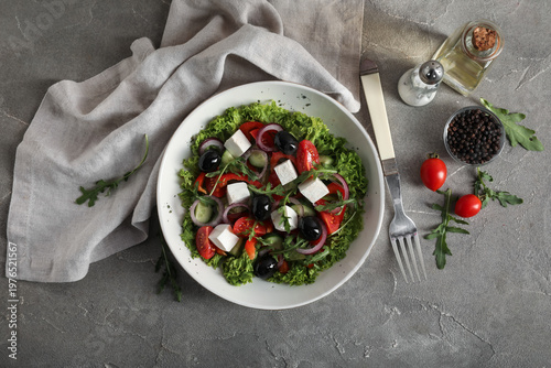 Composition with bowl of fresh Greek salad and ingredients on grunge background