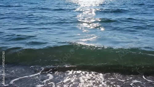Shimmering Ocean Waves Rolling Onto A Sandy Shoreline