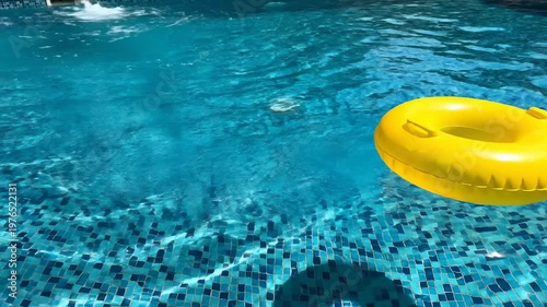 Yellow inflatable pool ring floating on clear blue swimming pool water