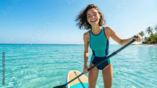 Young woman in blue swimsuit paddle boarding on turquoise ocean water, medium shot, eye level
