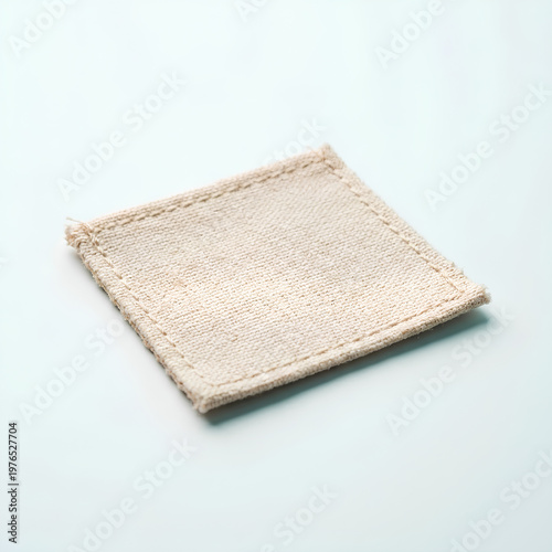 Square beige fabric coaster on a white surface simple and clean.