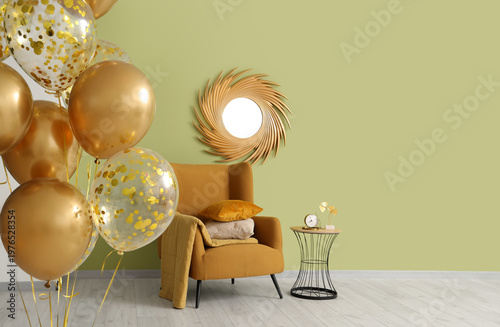 Golden air balloons, armchair and table near green wall in room