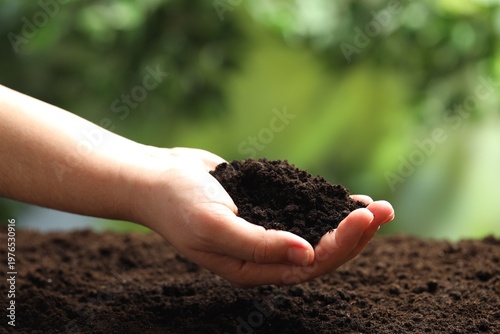 Woman with fresh soil on blurred background, closeup