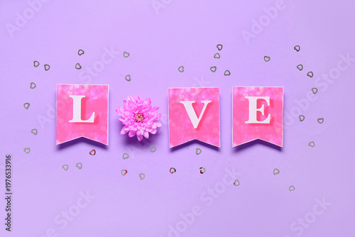 Word LOVE made of paper flags and chrysanthemum flower on purple background. Valentine's Day celebration
