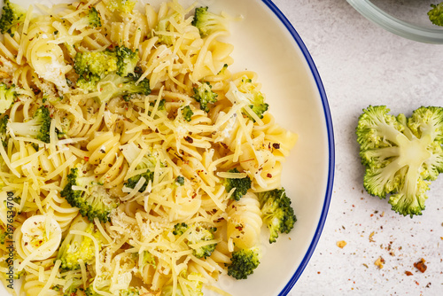 Delicious fusilli pasta with broccoli and cheese in bowl on light background, closeup