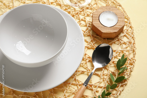 Beautiful table setting with candle and branch on beige background, closeup