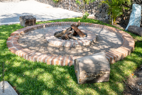 Foto Outdoor backyard brick fire pit with log seating
