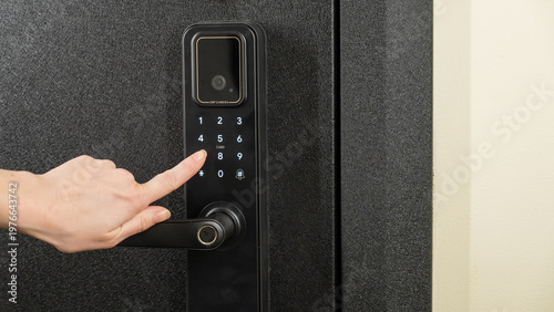 A woman opens a modern smart door lock with a digital keypad using a code.