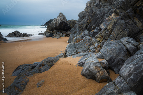 Praia da Adraga beach with rocks in the sea on a moody day, Sintra, Portugal. Travel and seascape banner