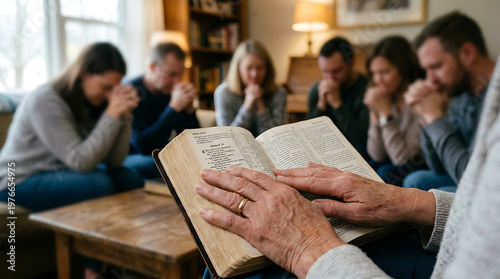 Multi-generational family praying together around an open bible at home