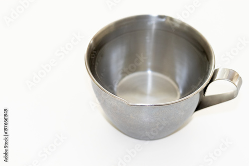 透明な液体で満たされた金属製の計量カップ