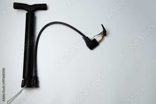 A black pump with several attachments and a leg handle lies on the side on a white background. High quality photo 