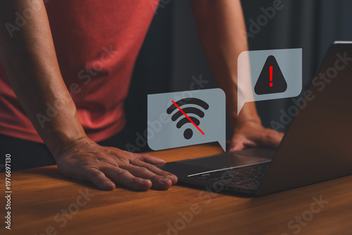 Man using laptop with warning sign and no wifi internet connection error symbol. Technology network problem, offline concept, and communication failure.