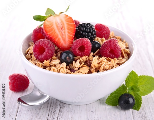 Close-up of granola and berries in a white bowl with mint
