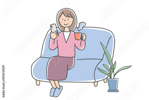 ソファで温かい飲み物を飲みながらスマホを見る女性