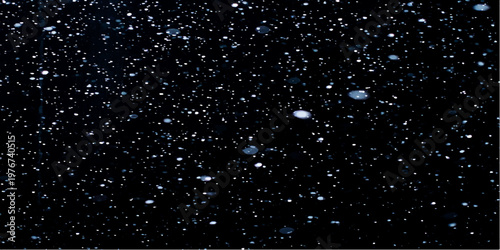 Rain drops on the window mingle with falling snowflakes against a dark blue night sky filled with glittery stars and festive Christmas light patterns for a winter holiday celebration background