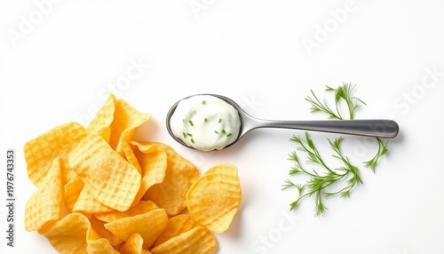 Golden potato chips arranged beside a spoonful of sour cream topped with chopped chives and a small bunch of fresh dill, styled as a clean, appetizing snack or party dip on a white backdrop.


