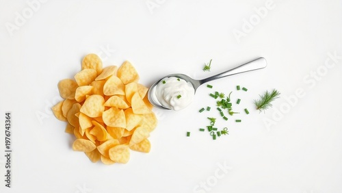 Golden potato chips arranged beside a spoonful of sour cream topped with chopped chives and a small bunch of fresh dill, styled as a clean, appetizing snack or party dip on a white backdrop.

