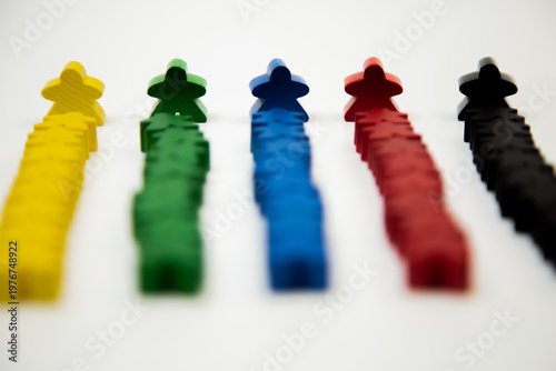 Side view of wooden multi-colored men in focus, who stand at the head of a column of smaller people on a white background. The concept of team competitions, social groups, managers, leaders. High