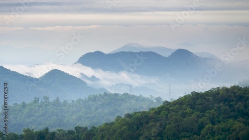 Time-lapse video of mist flowing through a valley There are lines of electrical transmission towers high on the mountain.