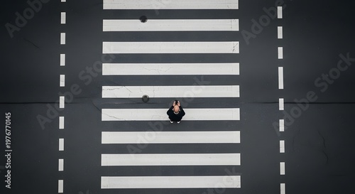 Aerial top view of a man using a smartphone while standing on a pedestrian zebra crossing, distracted walking concept