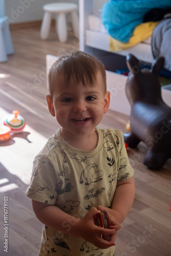 Obraz na plátně Smiling toddler playing with toys in a cozy home playroom Portrait