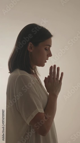 Woman in prayer position with hands clasped in peaceful meditation, vertical shot