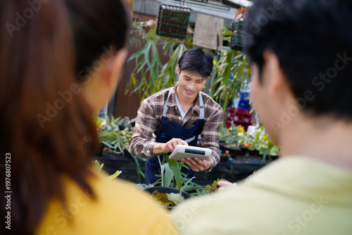 Fotografie Adult Asian man worker gardener wearing apron service customers, showing calcula