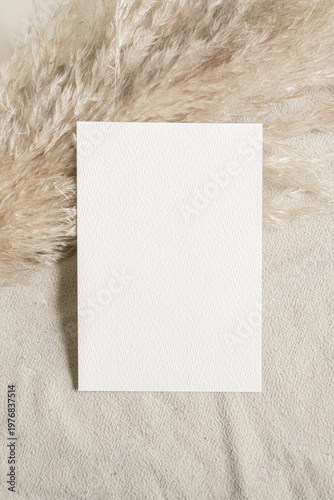 Small blank paper mockup on neutral fabric minimal soft light aesthetic composition clean template vertical copy space