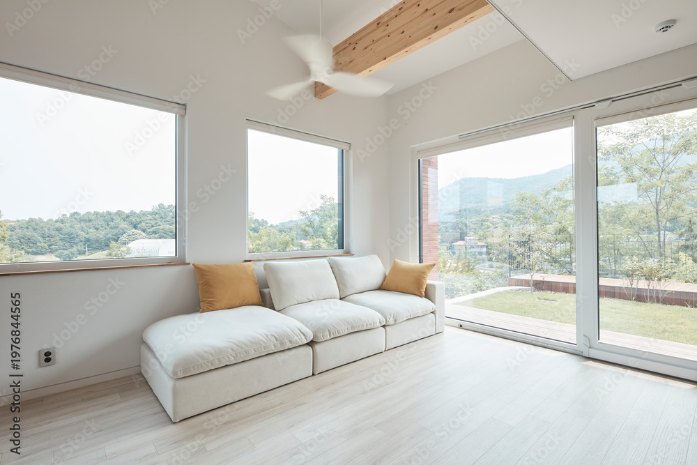 Fototapeta premium Bright living room with low sofa and broad windows in contemporary home