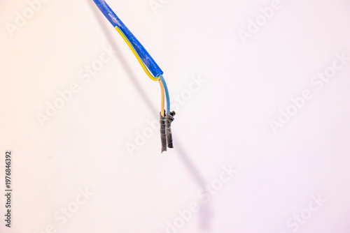 Fotografi Exposed electrical wires hanging from ceiling in unfinished indoor room, damaged insulation