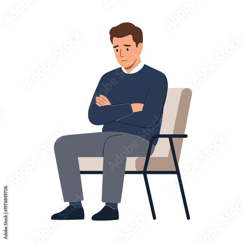 A man sits on a chair with his arms crossed looking down