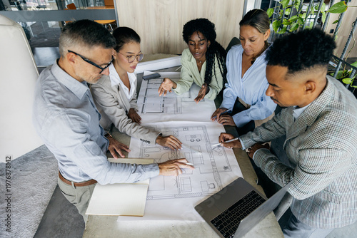Architects collaborating over blueprint table, diverse team
